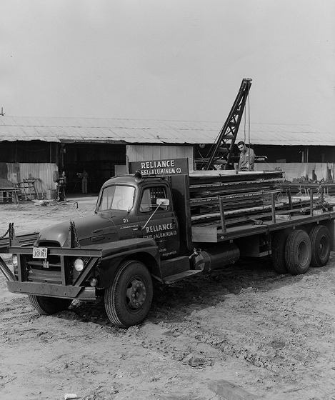Vintage Reliance Steel & Aluminum Co. truck loaded with metal stock in the yard.