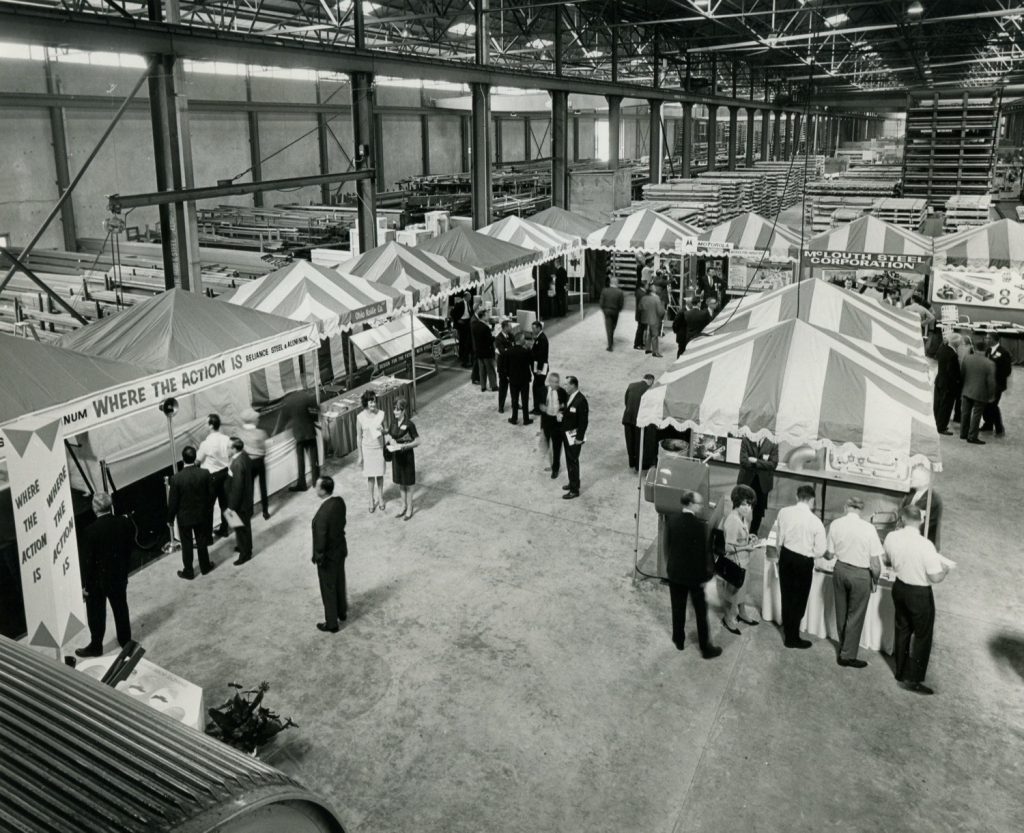 Vendor booths and attendees inside a large Reliance warehouse during an open house event.