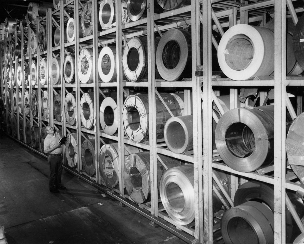 Warehouse racks filled with large steel and aluminum coils.