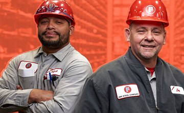Two industrial workers in red hard hats standing with arms crossed in a fabrication facility