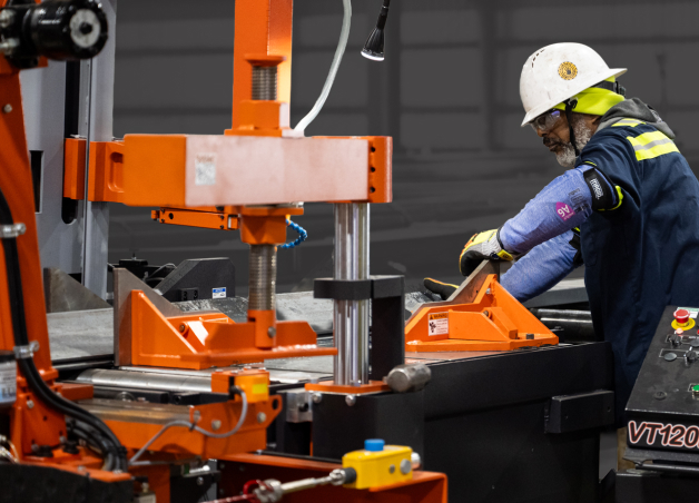 Worker operating an industrial metal cutting machine in a fabrication shop