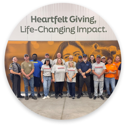 Volunteers standing indoors beneath a sign reading “Heartfelt Giving, Life-Changing Impact.”