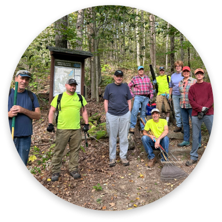 Volunteers on a wooded trail with cleanup tools.