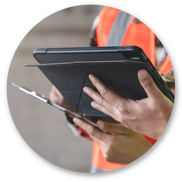 Workers in safety vests using a tablet and clipboard to review job site information.