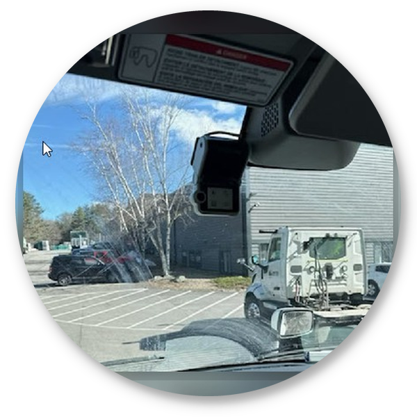 Interior truck view showing a dashboard safety camera and a vehicle outside through the windshield.